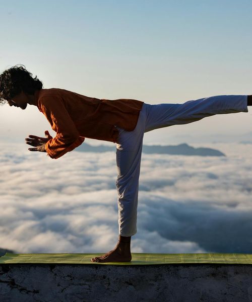 Silhouette of a man stretching against a sunrise, symbolizing well-being.
